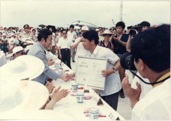1594526018988020499.png 1990年7月4日,溫州機(jī)場舉行上海至溫州首航典禮,中國民航局副局長李釗給溫州民航站站長張德志頒發(fā)機(jī)場使用許可證.png